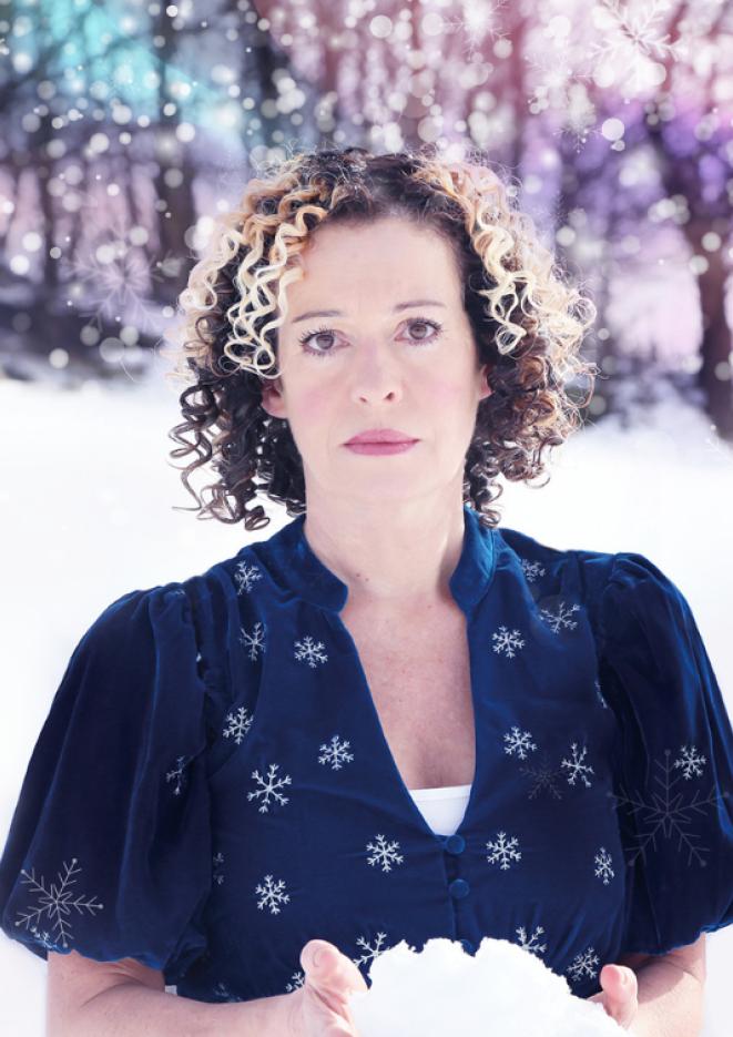 Singer Kate Rusby stands against a background of snow and trees.