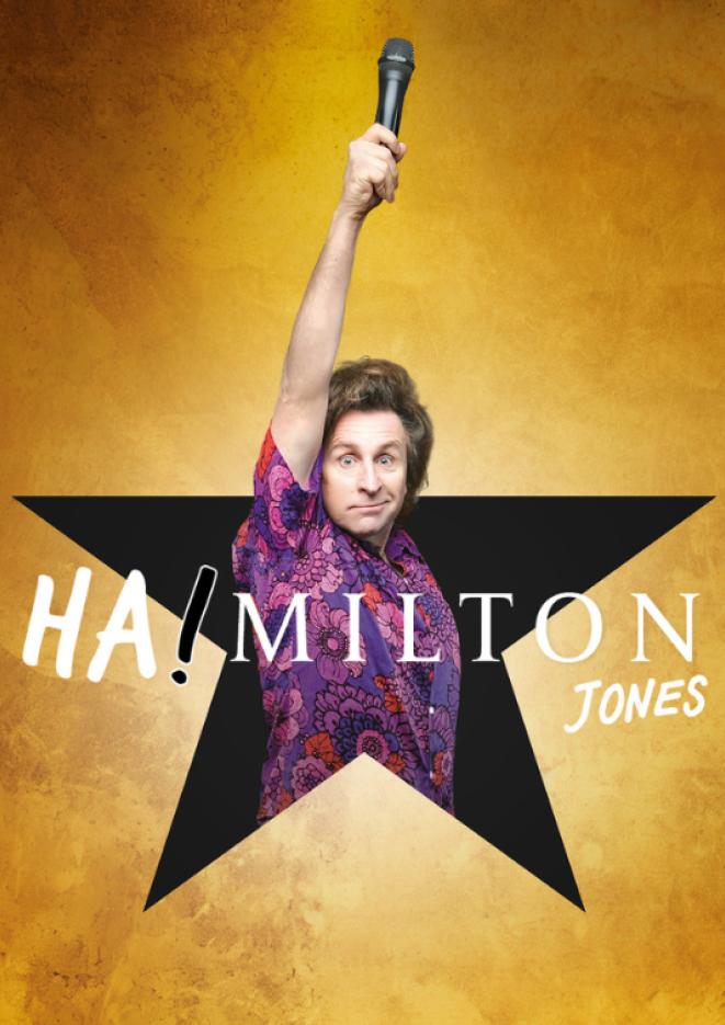 Comedian Milton Jones stands in the centre of a black star holding a microphone up in the air. 