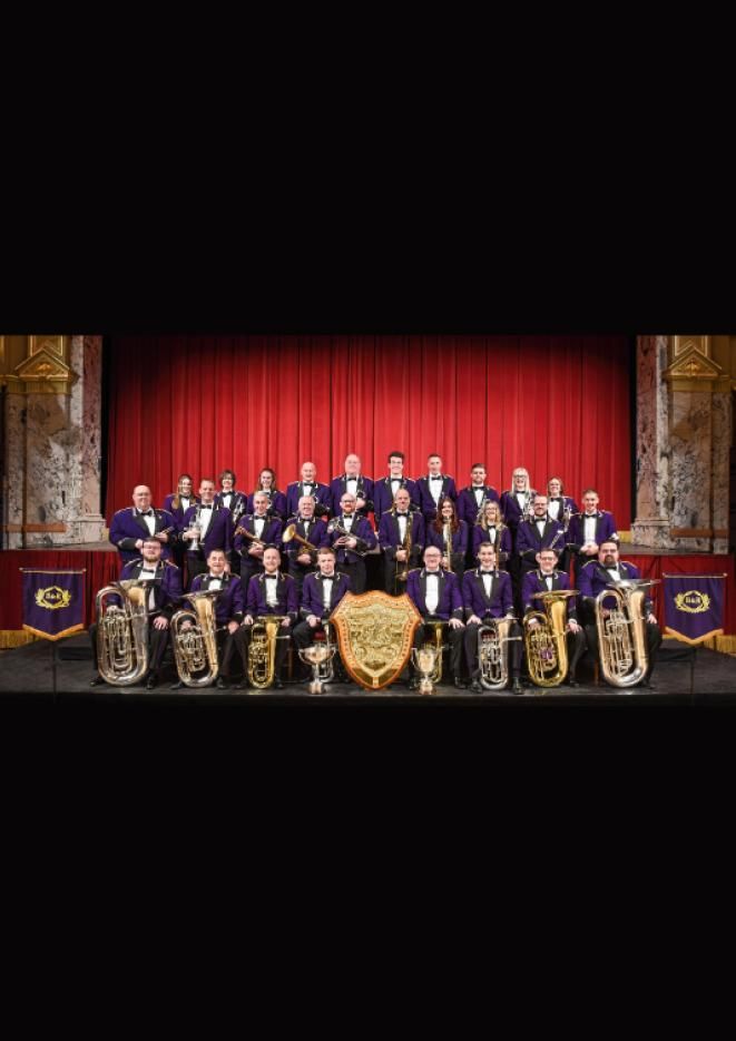 A brass band sitting against a red backdrop