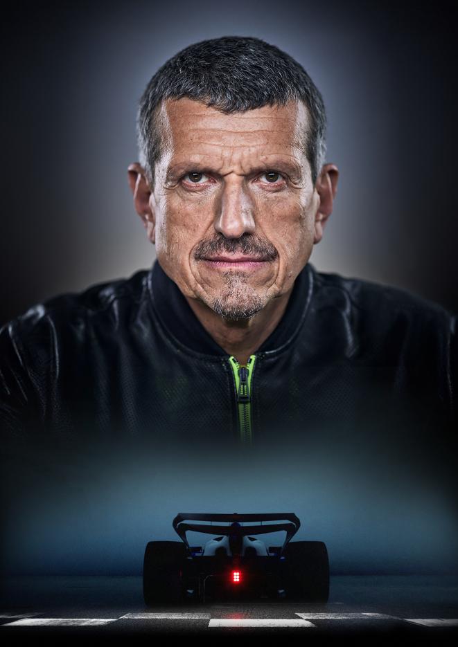 Image of Formula One personality Guenther Steiner against a black background with an F1 car underneath.