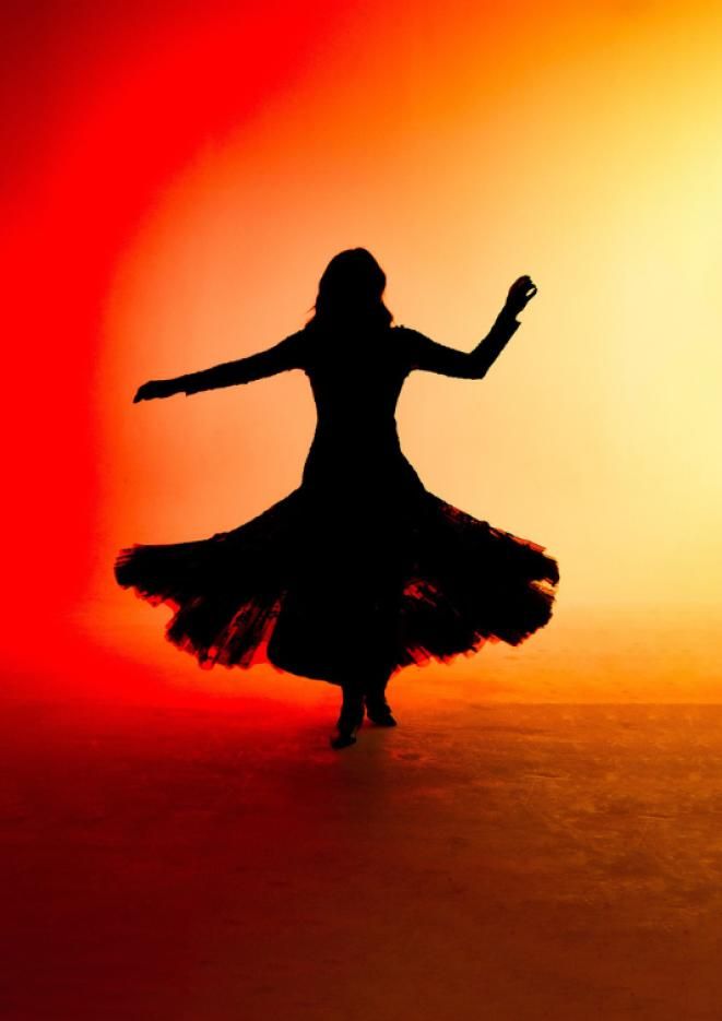 A silhoutte of a woman dancing while wearing a long skirt, against a red and yellow background.