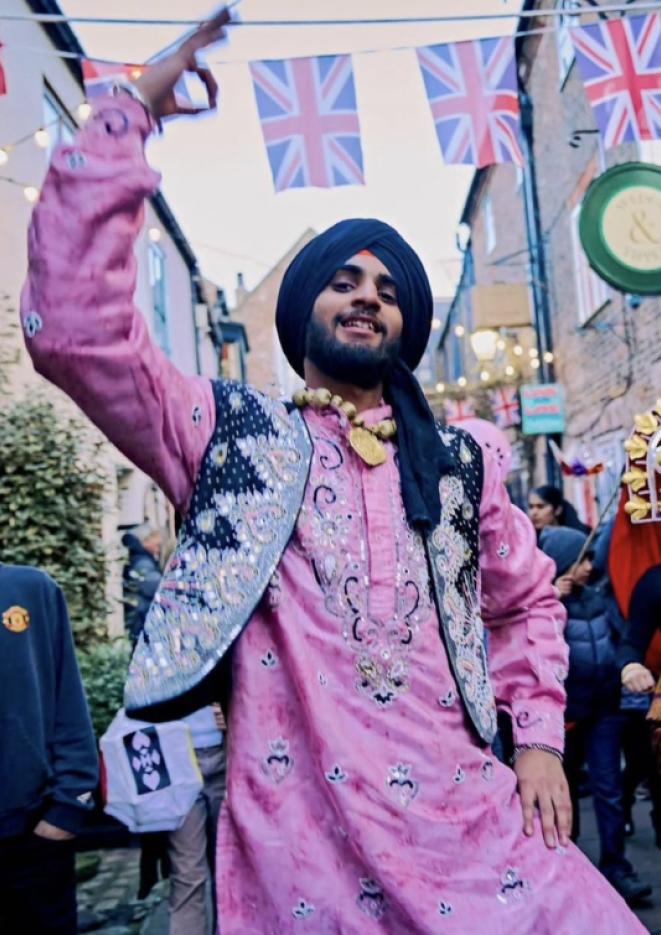 A man dancing in a street wearing a pink and black outfit.